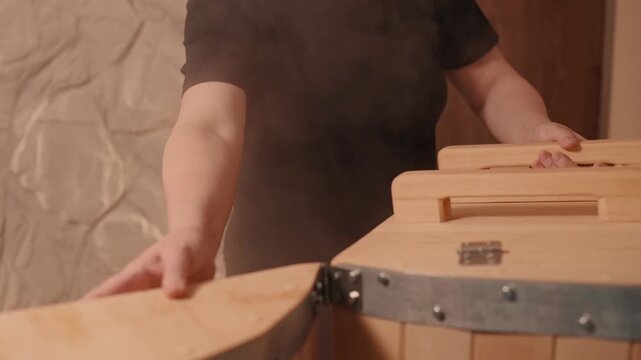 Woman prepares for cedar hot herbal barrel treatment at spa. 