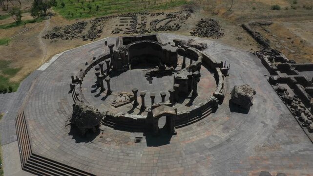 Aerial drone footage reveals the spectacular ancient stone ruins of Zvartnots Cathedral in Armenia. The top-down perspective highlights circular columns, intricate foundations, and tourists exploring 