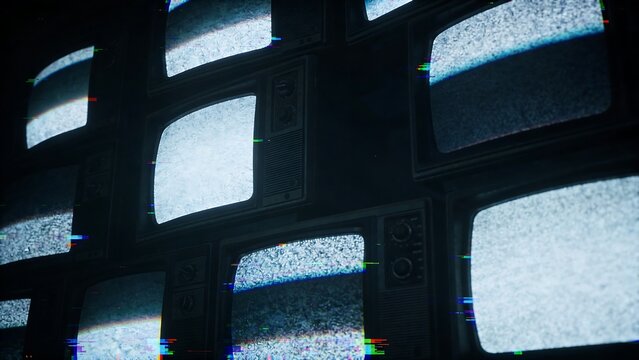 Several old televisions were stacked in a dark room, displaying static and flickering images, giving the feeling of being spied on.