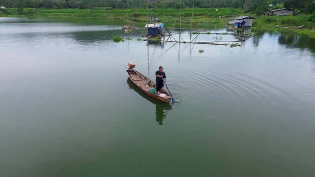 4K Aerial Drone View of Traditional Fisherman Casting Net from Wooden Boat on Lake in Malang Indonesia