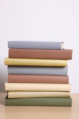 Fototapeta premium Stack of different books on wooden table against light background