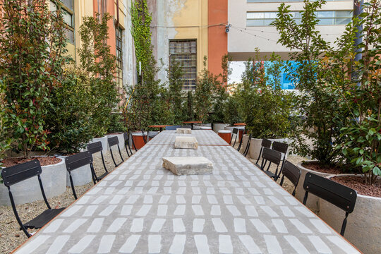 Outdoor communal table with black chairs in courtyard of Manifattura Tabacchi, Florence, Italy