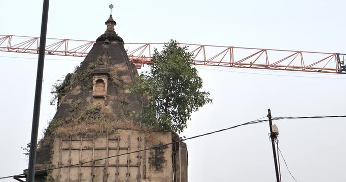 Urban construction is causing damage to an old temple, highlighting heritage destruction and the impact of rapid city development on cultural sites
