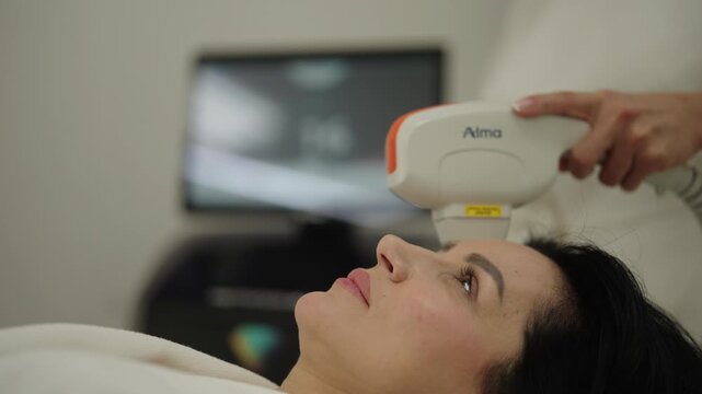 Ufa, Russia - 27 January 2026. Relaxed woman receiving modern hardware cosmetology procedure for facial skin rejuvenation from a beautician, non invasive treatment for anti aging and skin tightening.