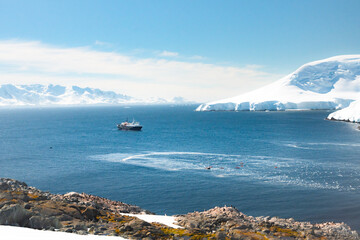 Expedition Cruise Ship and Kayakers in Antarctic Bay with Gentoo Penguin Colony - Scenic Polar Voyage in the Southern Ocean near the Antarctic Peninsula © Nick