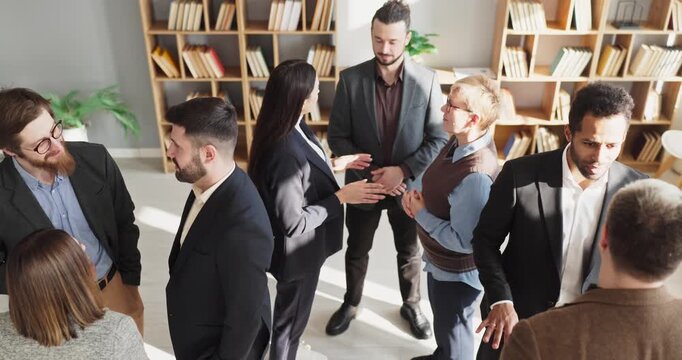 Team colleagues professionals in business meeting networking. Small groups talk across a bright office, sharing discussion and ideas. Professional workplace communication and networking.