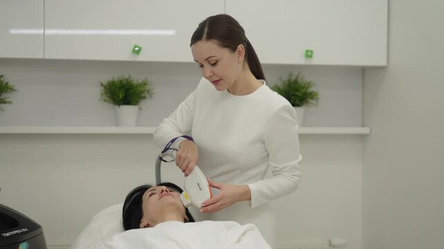 Ufa, Russia - 27 January 2026. Skilled esthetician providing non invasive skin rejuvenation treatment with professional ipl device to female patient, enhancing facial beauty and wellness in spa salon.
