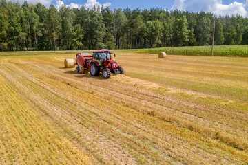 Obraz premium MINSK, BELARUS - JULY 2020: tractor removes straw in the field after harvesting