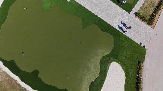 Overhead view of unrecognizable golfers meeting on putting green practice area