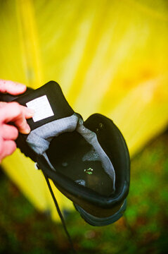 A boy holds his water-filled boot after a cold, wet night in the North Carolina mountains while hiking in winter.