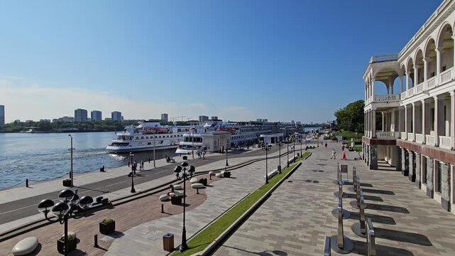 MOSCOW - JUL 26 , 2025: City street with a large building Stalin era riverside station in the background. The street is lined with trees and benches