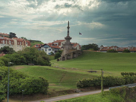 Comillas Monumental View Under Dramatic Sky - Monument and village of Comillas, Cantabria, Spain, featuring green hills and historic architecture under a cloudy, atmospheric sky.