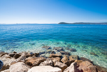 a beautiful beach with a view of the Adriatic Sea with rocks on the shore and pine trees in Split, Croatia © Sheviakova