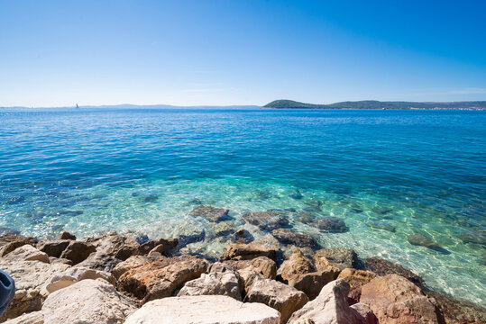 a beautiful beach with a view of the Adriatic Sea with rocks on the shore and pine trees in Split, Croatia