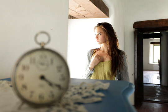 Young woman looking out window in soft natural light