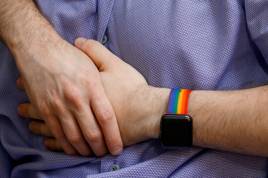 Close-up of couple holding hands with rainbow pride bracelet