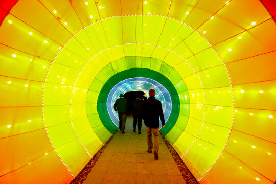 People Walking Through Colorful Light Tunnel Symbolizing Journey and Transition