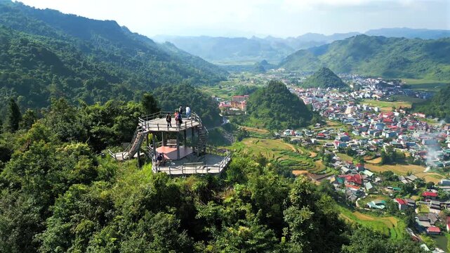 Aerial view of a group of tourists on a wooden observation deck admiring the stunning scenery of Tam Son valley and the surrounding mountains