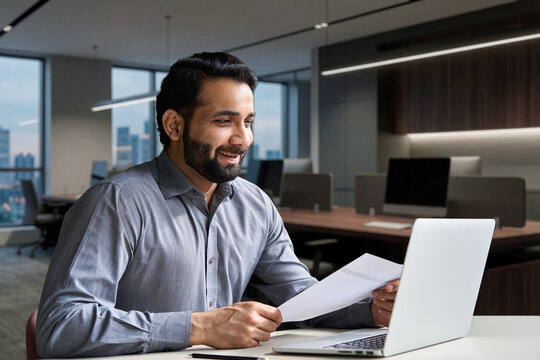 Smiling indian business man hr employer, teacher or lawyer holding cv document having virtual job interview meeting by video conference call, consulting client on laptop at online legal advice.