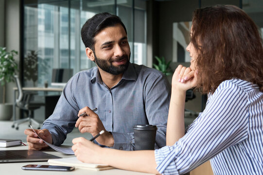 Interview of happy smiling indian hr manager with latin young professional and friendly support discussing job cv. Mentoring Hispanic male teacher and female student in multiethnic creative space.