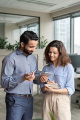 Diverse friendly coworkers talking using digital tablet in office. Indian manager having discussion...