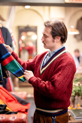 Man customer with mustaches buys clothing in stylish men's apparel boutique, looking and choosing...