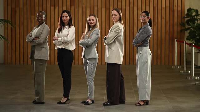 Diverse team of confident businesswomen standing with arms crossed looking at the camera, promoting female leadership