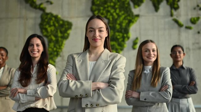 Diverse international businesswomen standing proud in front of a green world map, showing leadership and success