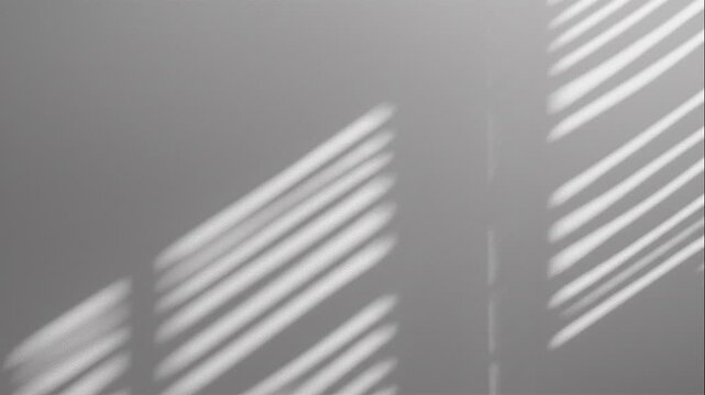 Shadows cast by window blinds create parallel lines on a plain wall, forming an abstract pattern in soft, diffused light