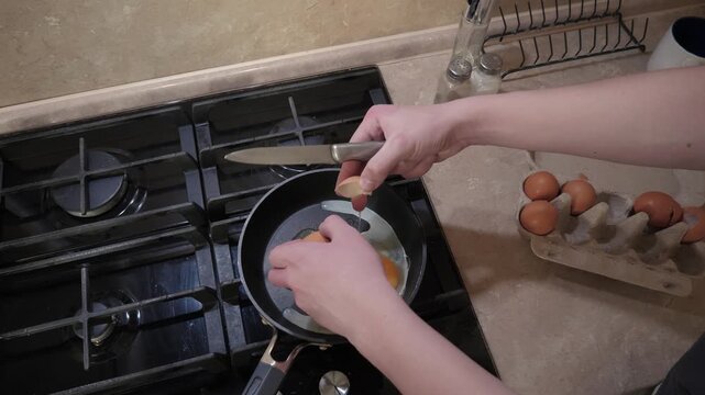 Preparing breakfast eggs in cozy kitchen. Homemade breakfast begins with frying eggs in skillet early morning. Starting day with freshly cooked eggs by homemaker in warm kitchen environment