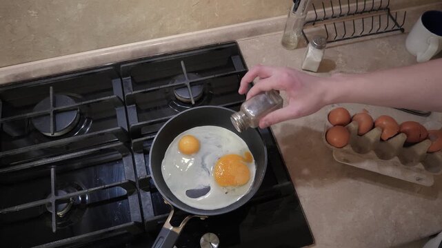 Cooking eggs calmly. Preparing breakfast with care. Home chef making quick morning eggs. Frying eggs on stove in cozy kitchen scene. Kitchen shot with eggs sizzling and peaceful morning ambiance