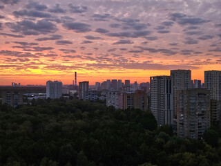 Fototapeta premium The sky is orange and the sun is setting. The city below is lit up with lights