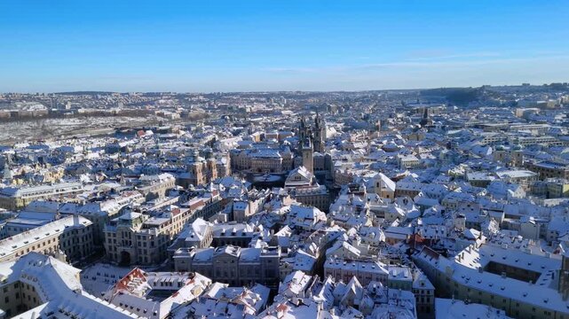 Aerial view of Prague Old Town Square in winter. Snow-covered rooftops, T&yacute;n Church, and sunny blue sky. Stunning historic Czech Republic cityscape