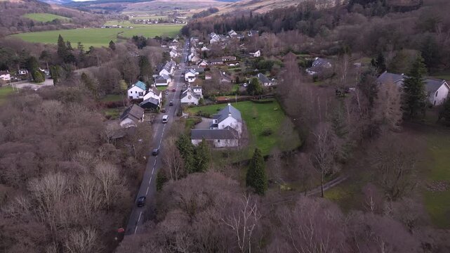 A low level flight along the main street of a picturesque rural village in Central Scotland nestled in a valley below the Campsie Hills. No road signs or location markers.
