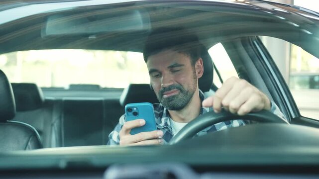Young man sitting in the car and typing on the smartphone. Slow motion