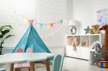 Child's room with furniture, toy wigwam, toys and colorful flags. Interior design © New Africa