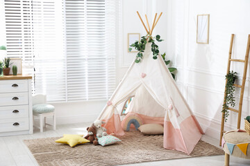 Toy wigwam with pillows, furniture and floral decor in room © New Africa