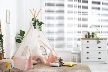 Toy wigwam with pillows, furniture and floral decor in room © New Africa