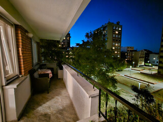 Naklejka premium Balcony overlooking a city at night. The city is lit up with lights and the balcony is empty