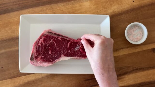 Seasoning a New York Sirloin Steak with Salt and Pepper