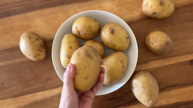 Taking some Potatoes from a Bowl of Yellow Potatoes
