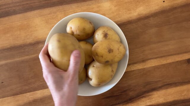 Taking some Potatoes from a Bowl of Yellow Potatoes