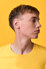 Naklejka premium Man profile in a yellow shirt, side view against a yellow background, showcasing clean lines, calm expression, modern fashion aesthetic, versatile stock image