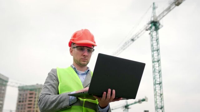 Man inspects territory of construction site outside, use gadget