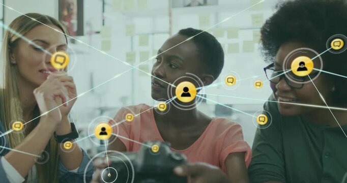 Animation of connected icons over diverse female coworkers sharing ideas in office