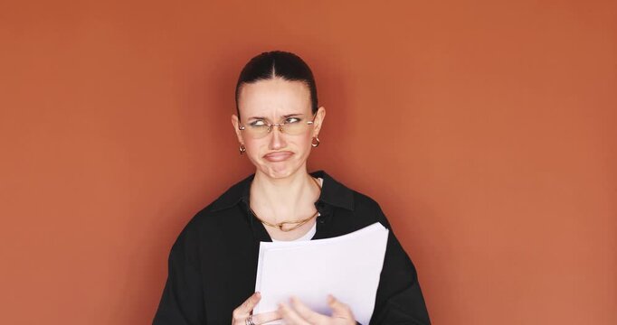 Stressed and frustrated woman looking at documents with shock and disappointment against brown background. Annoyed female office worker or student holding papers and reacting to bad news or failure