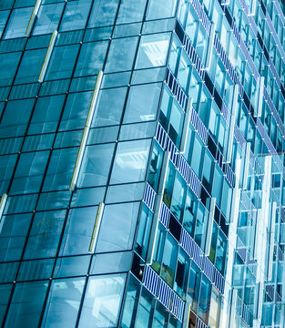 Abstract glass facade of modern office building with geometric pattern, reflections and blue tones in contemporary urban architecture