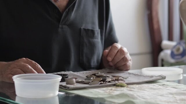 Numismatist examining antique coins with a magnifying glass. Male collector appraising his vintage money collection