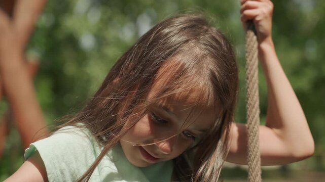 Child clutching cord in sunlight. Child holding rough cord beneath gentle summer sunshine outdoors. Young girl firmly gripping textured rope while basking in warm summer sunlight outside