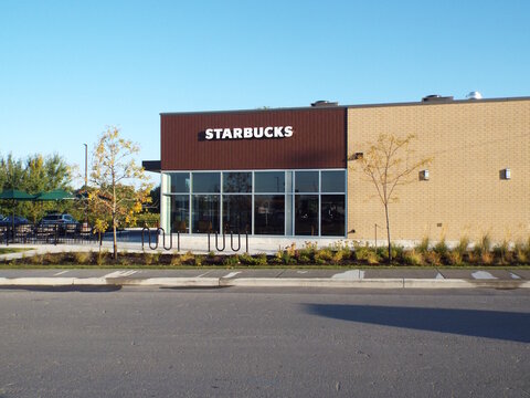 Gloucester, Ontario, Canada &ndash; July 24, 2025: A modern "Starbucks" cafe with wood and brick siding features large windows and outdoor seating under a clear blue sky at 140 Blanca St.